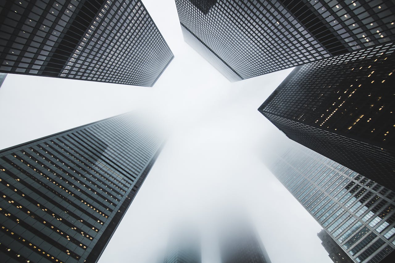 Misty city scene with towering skyscrapers disappearing into the fog, creating a moody urban environment.