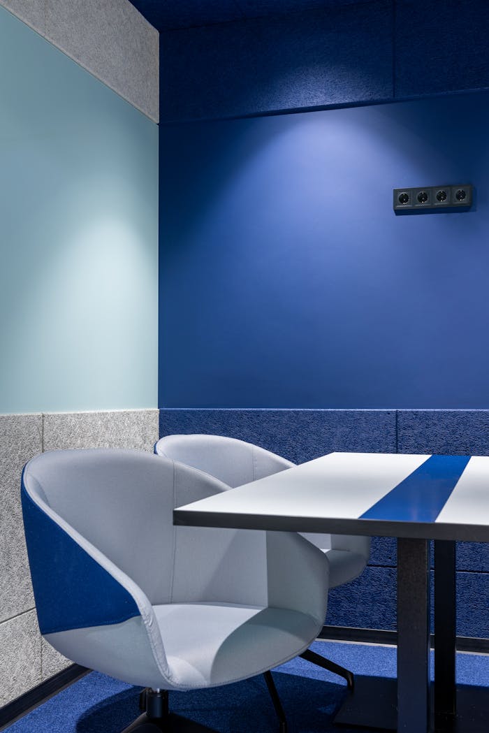 services-03 Comfortable armchairs at white table placed near blue wall in modern small workspace with stylish design in contemporary business center